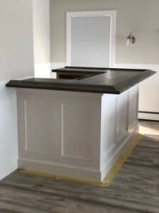 Dark stained hard maple bar top on a painted wood bar front.